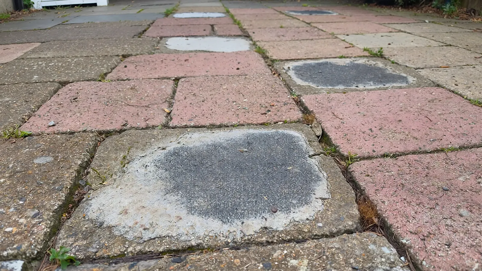 A repaired outdoor surface that continues to shift due to unresolved ground settling issues beneath it.