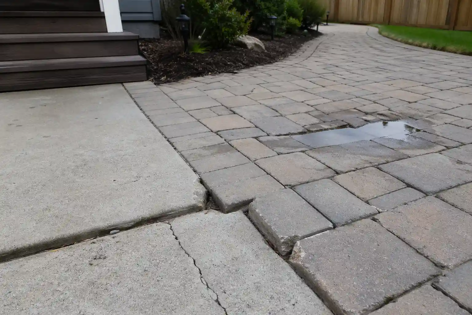 Outdoor patio and walkway surfaces failing early with chipped edges, open joints, cracking, and damp low spots